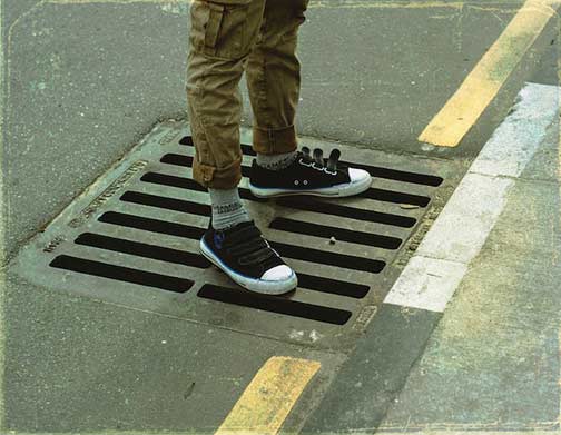 Man standing on road sewer grating