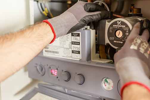 A plumber repairing a power source while wearing protection gloves.