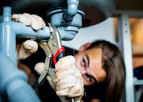 a plumber fixing a sink after a sewage backup.