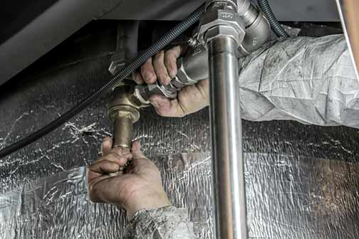 A plumber fixing silver pipes at a home.