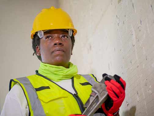 A woman in a uniform holding a plumber wrench.