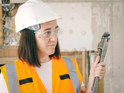 A plumber holding her plumber wrench.