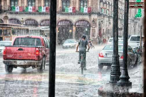A man riding his bike on a rainy day.