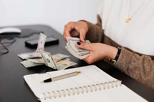 A woman counting money on the desk.