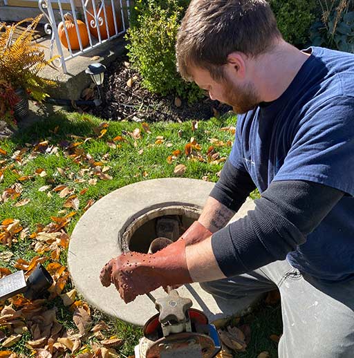 a person cleaning a catch basin out.