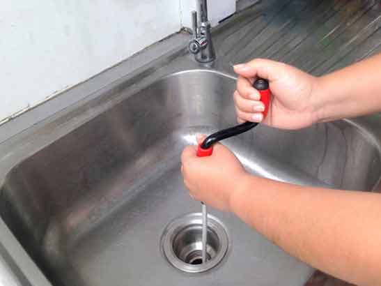 a man fighting drain clogs in his sink.