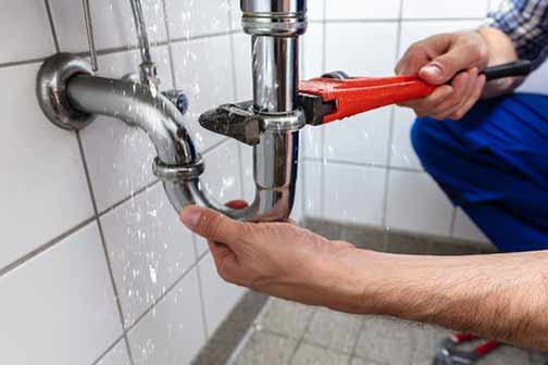 a person fixing a plumbing leak