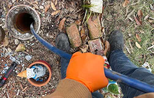 a plumber performing a hydro jetting drain cleaning service.