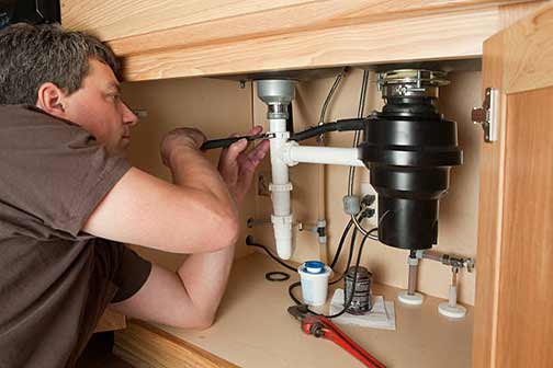 a man working on kitchen plumbing