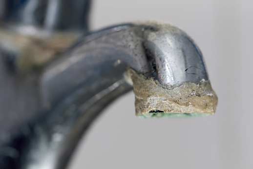 a sink faucet with limescale buildup.