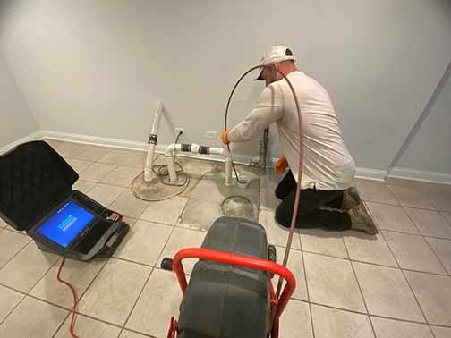 a plumber performing a sewer camera inspection in an older home