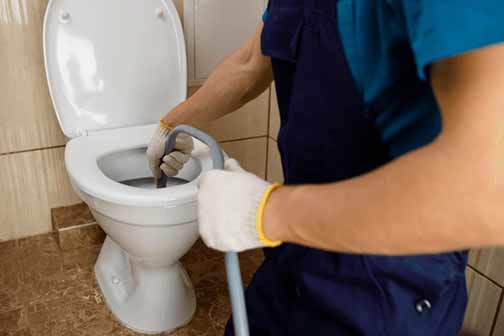 a plumber fixing a clogged toilet drain