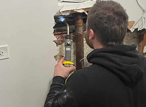 a professional plumber performing a burst pipe repair.