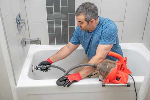 a professional plumber clearing out a shower drain.