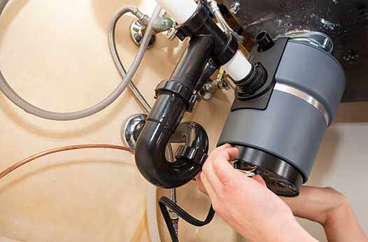 a plumber repairing a garbage disposal unit.