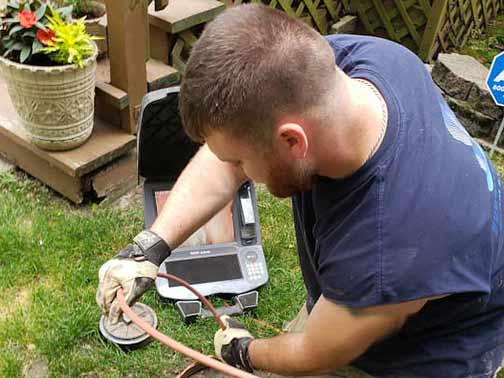 a plumber performing a sewer camera inspection to inspect for tree roots.