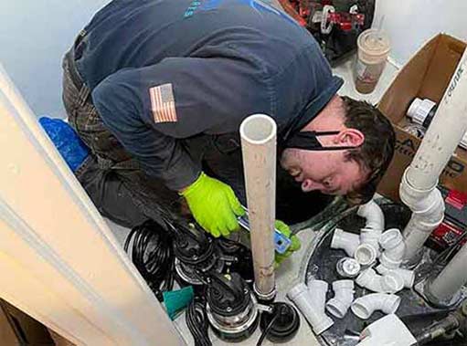 a plumber installing a sump pump in the basement of a hickory hills home.