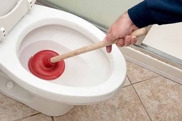 a man tying to unclog a toilet due to sewer backup.