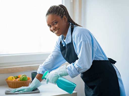 a woman cleaning around kitchen drains.